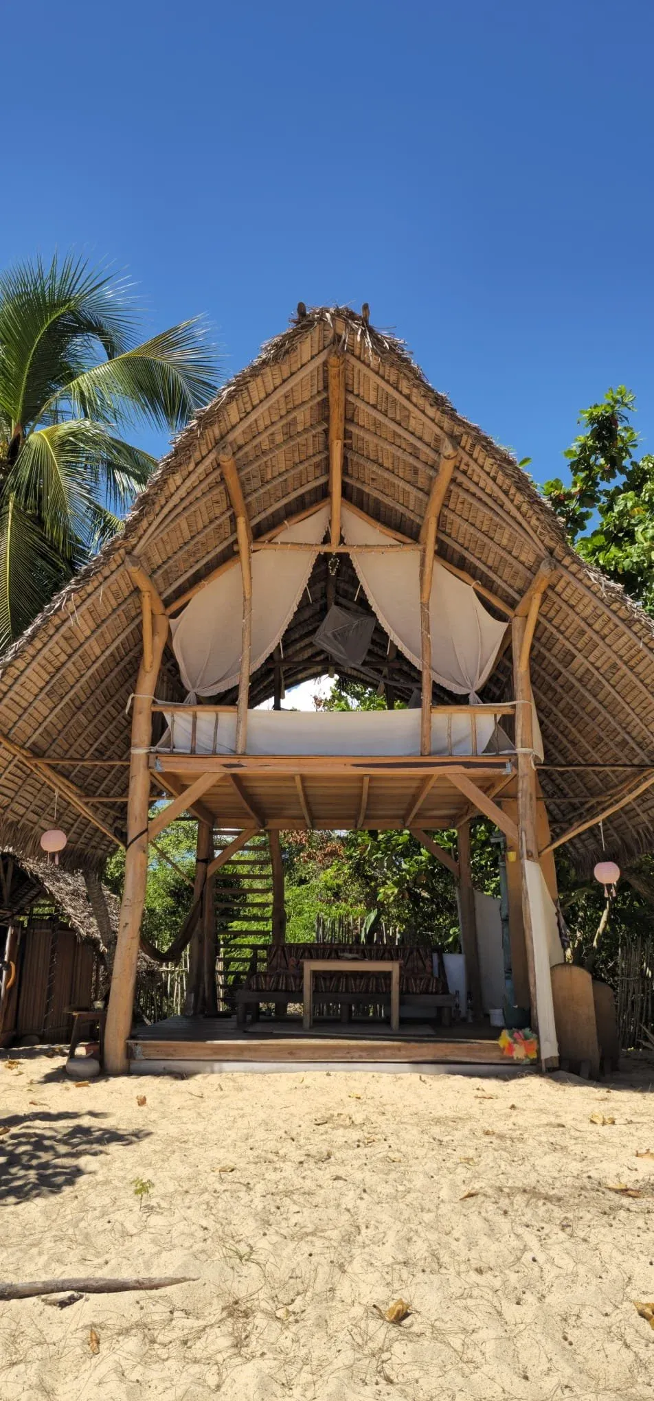 Das zweistöckige Spirit Beach Bed mit Palmdach und weißem Himmelbett am Strand von Ampohana